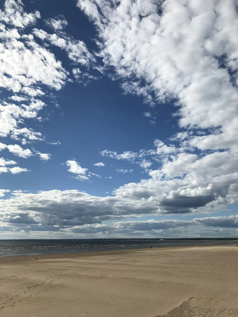 a sandy beach under a cloudy blue sky