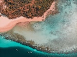 Aerial view of the turquoise waters and coral reefs at Muro Alto beach during sunset.