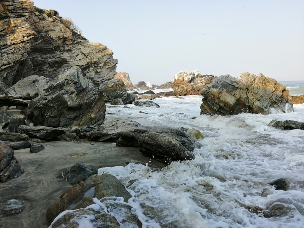 photography of ocean wave crashing on brown rock during daytime