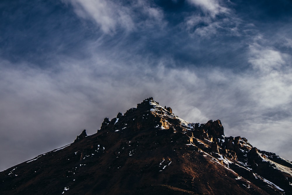 rocky mountain under white and blue clouds