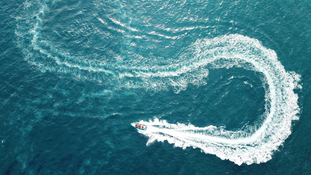 fotografia aerea della barca che fa il modo di zig zag sullo specchio d'acqua