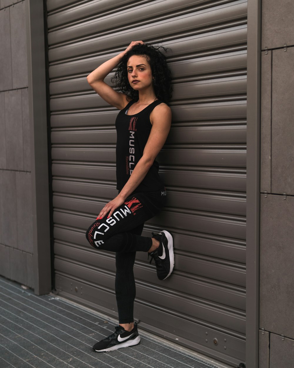 woman standing against the wall and touching her hair