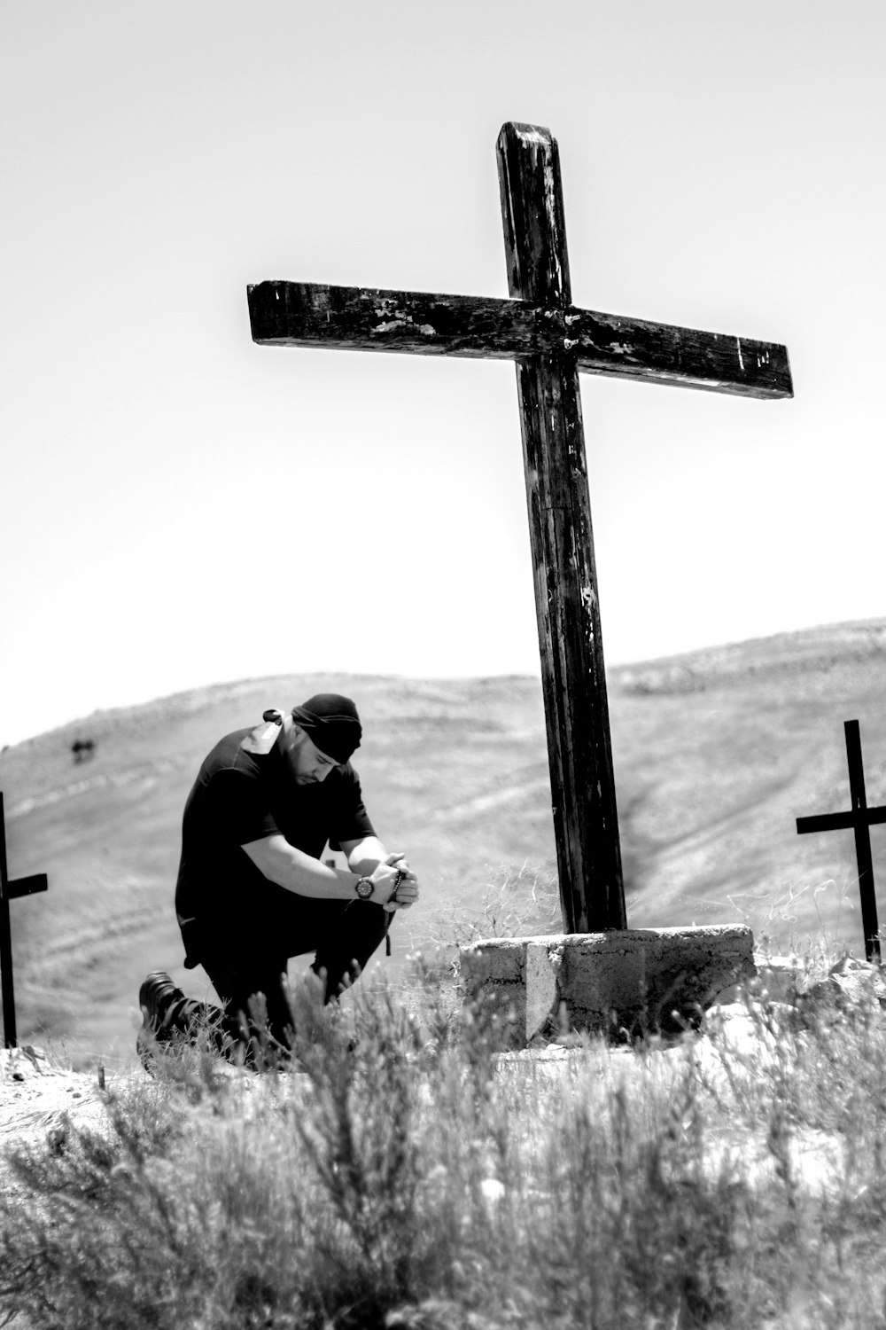 homme agenouillé devant une croix en bois