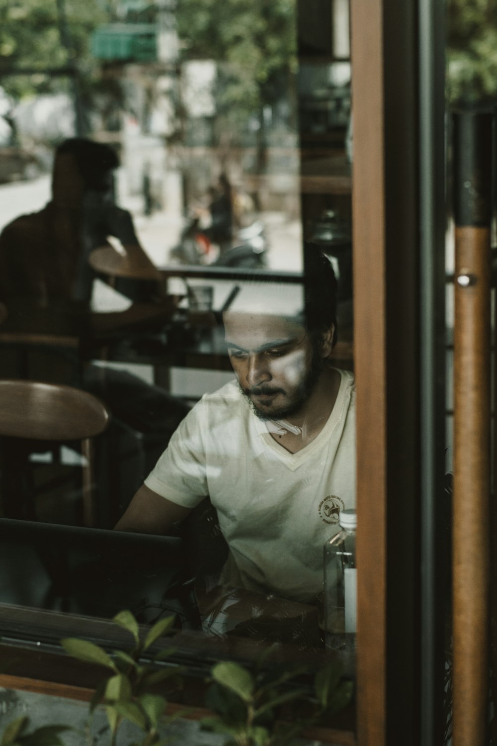 shallow focus photo of man in white V-neck T-shirt using laptop computer