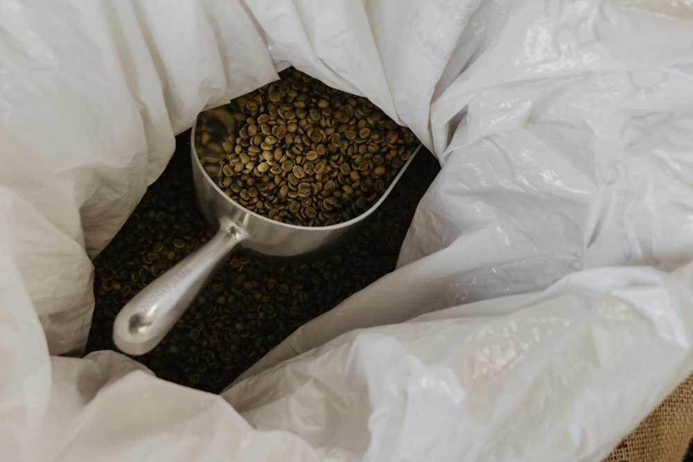 grains de café dans une cuillère en acier inoxydable