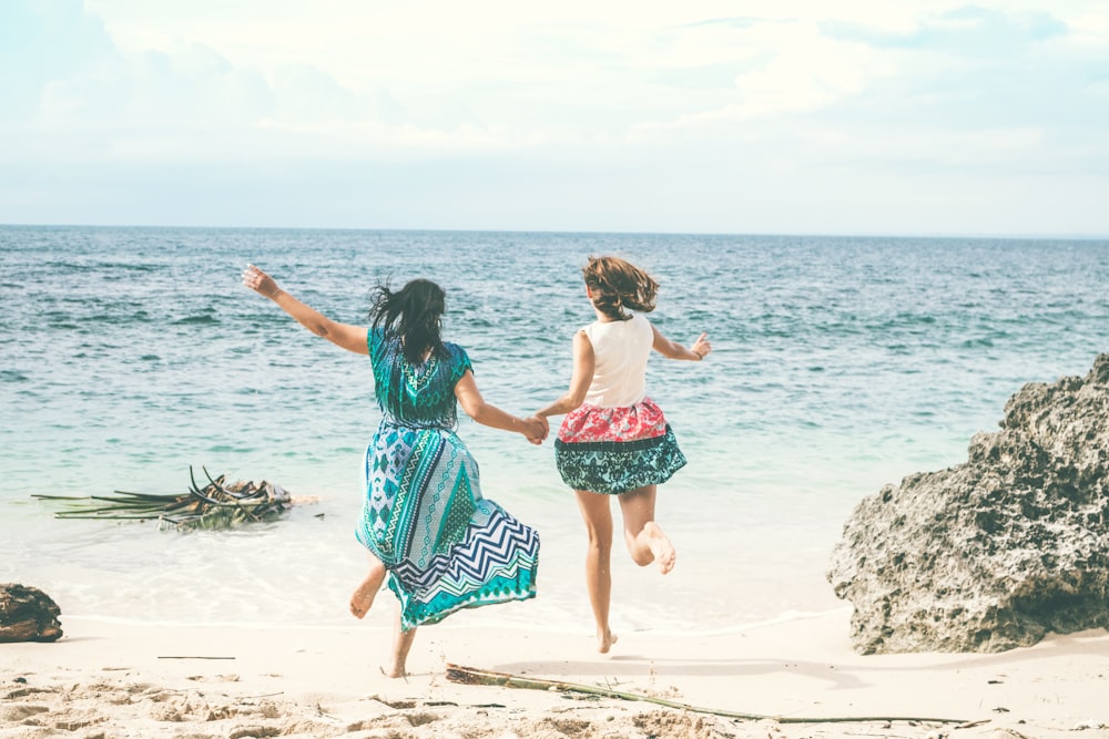 duas mulheres correndo em direção ao mar