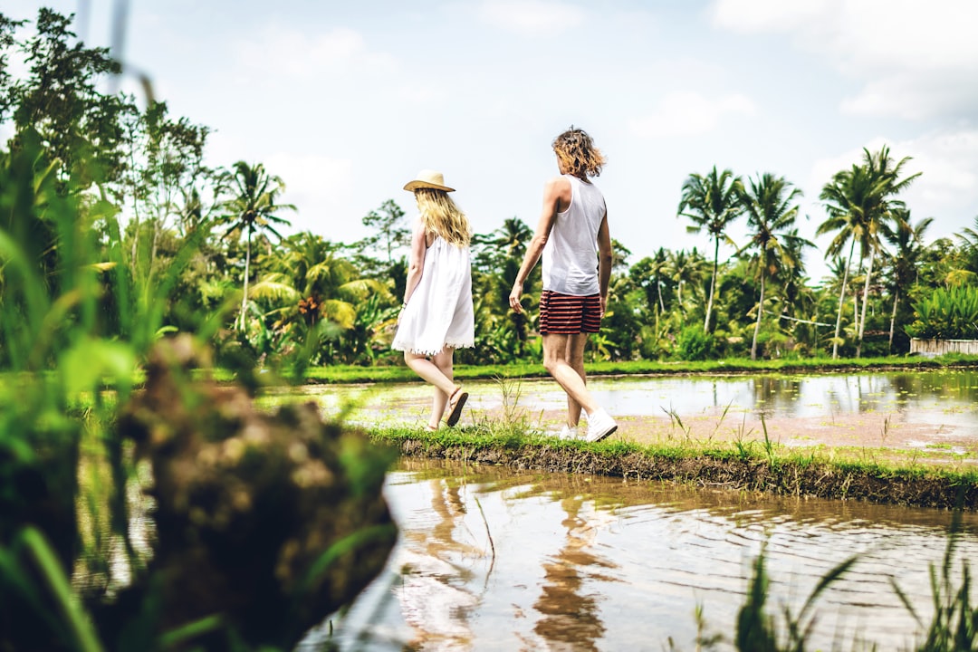 man and woman walking in rice field