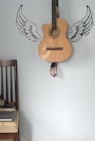 acoustic guitar hanging on wall with angel wings
