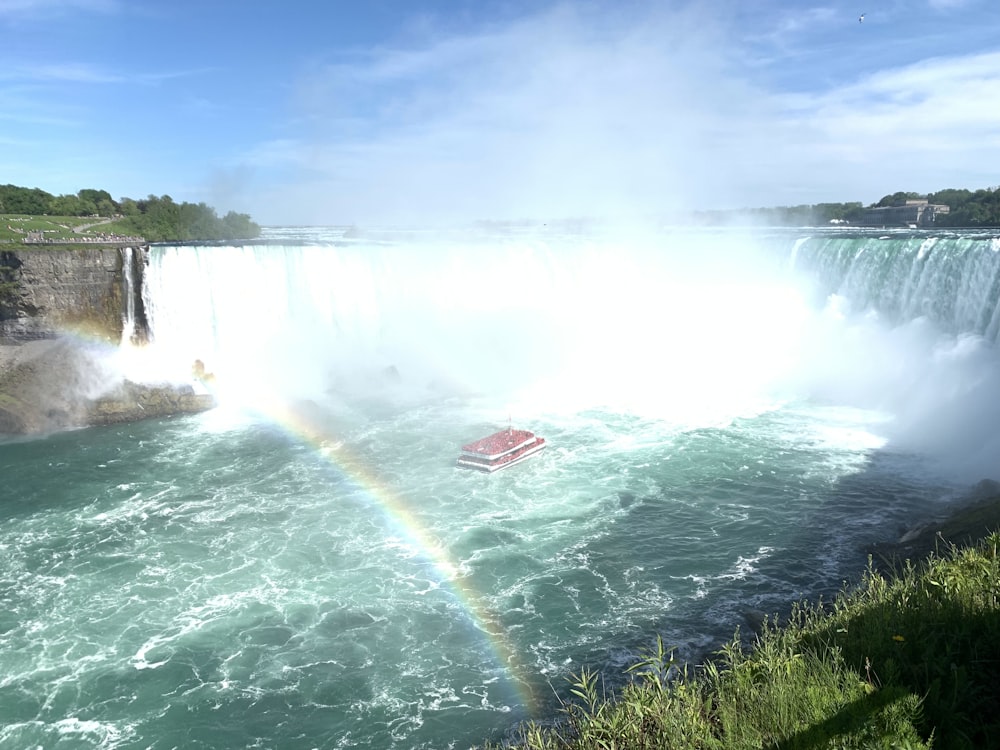 red ferry sailing near water falls