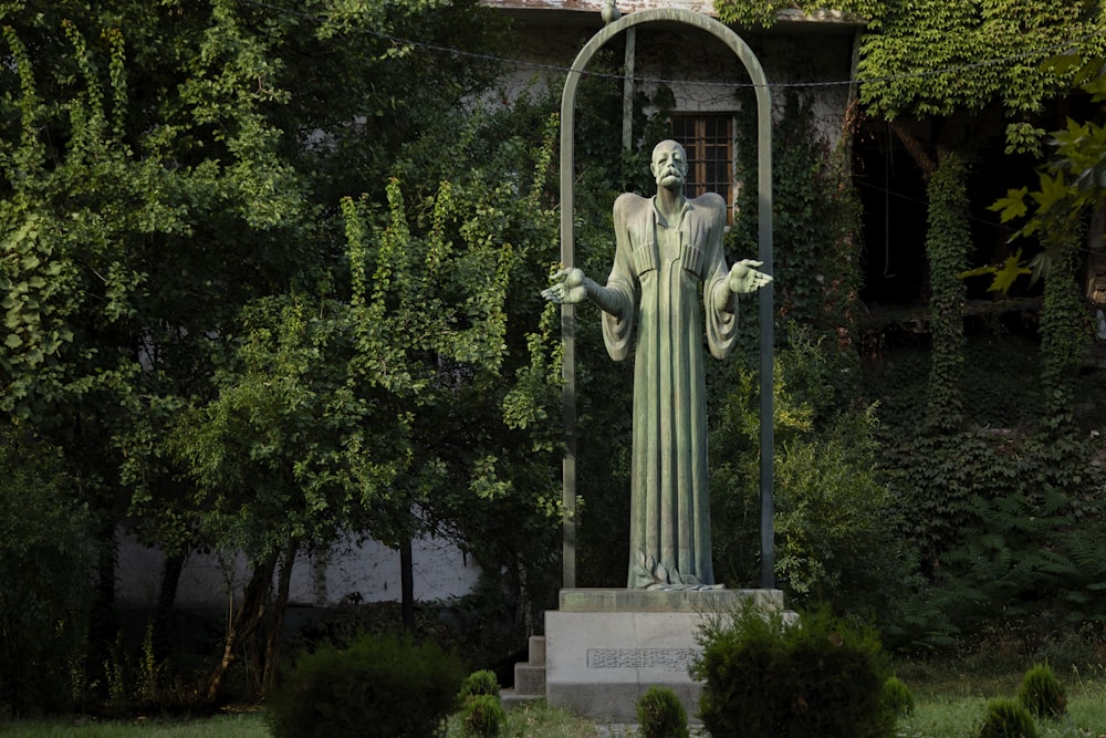 green statue in front of building covered with plants