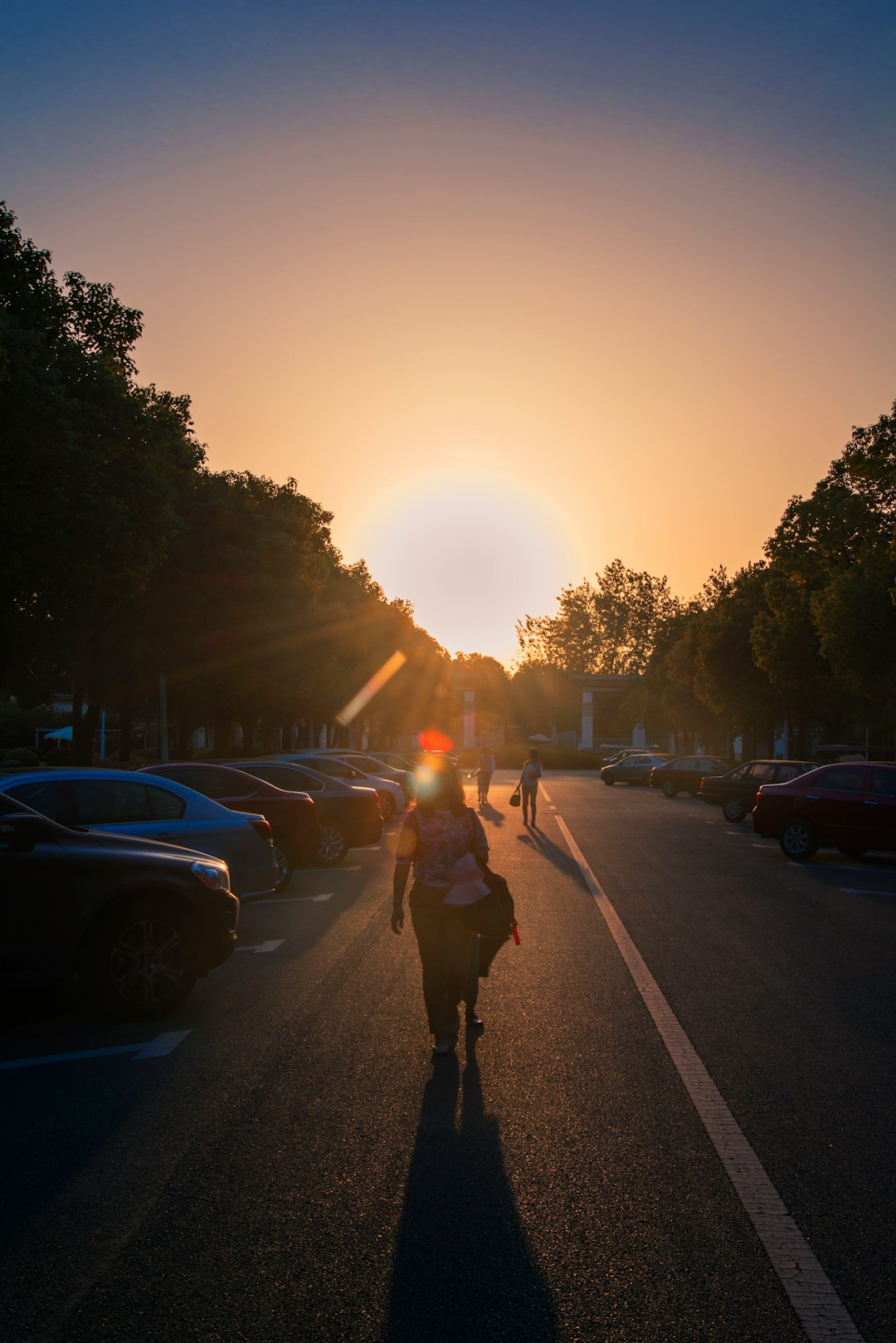 three persons walking at the parking lot during golden hour