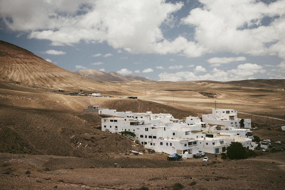 white buildings near brown mountain under white clouds