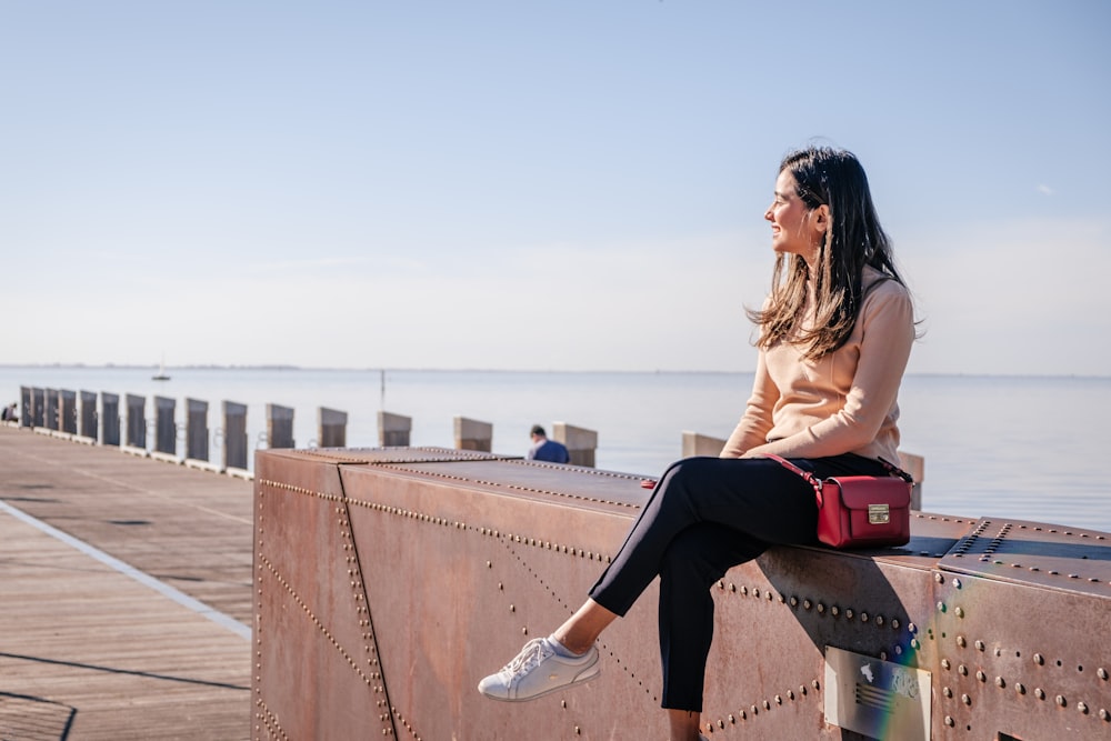 sitting woman wearing pink sweater and black leggings during daytime