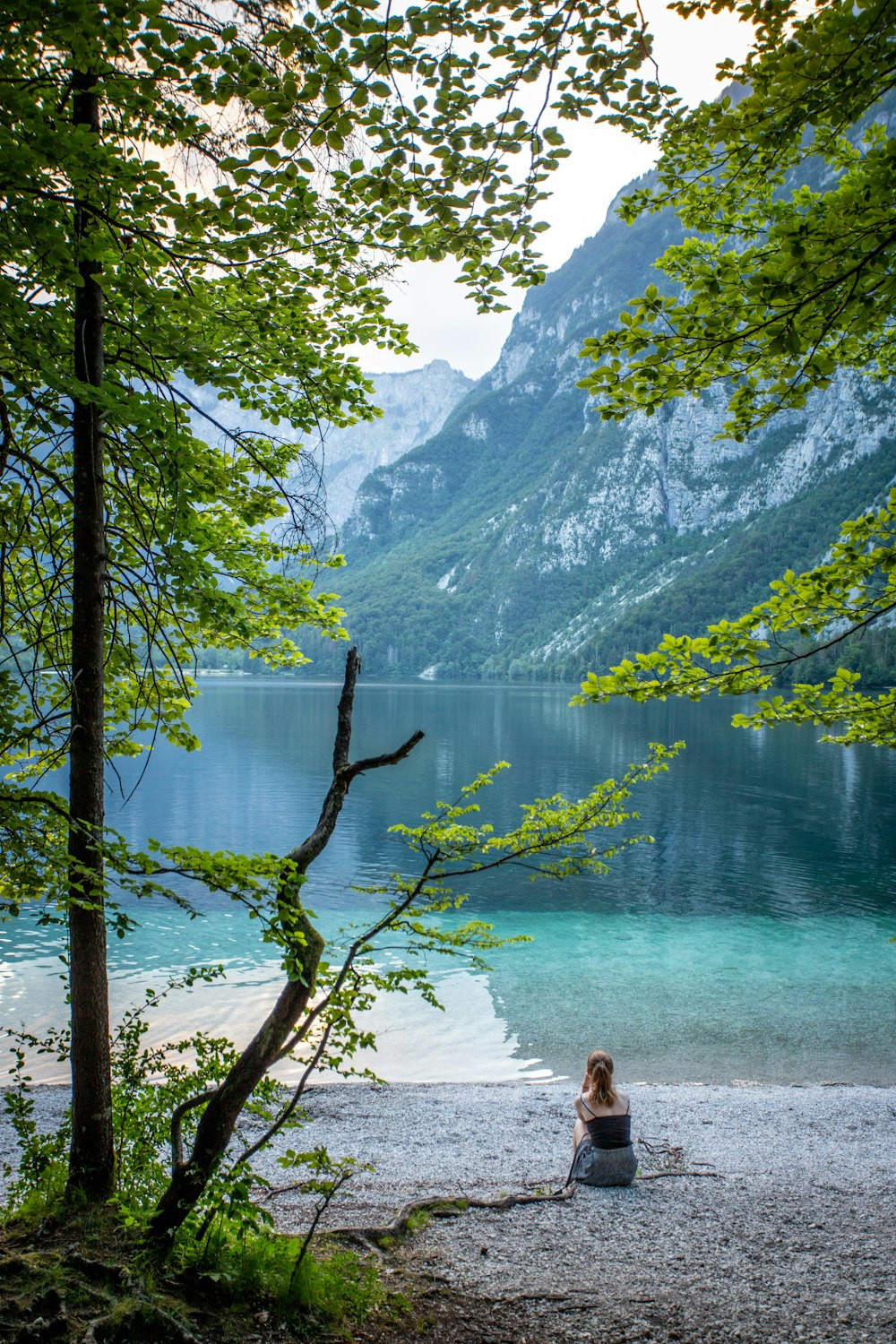 woman sits near lake at daytime