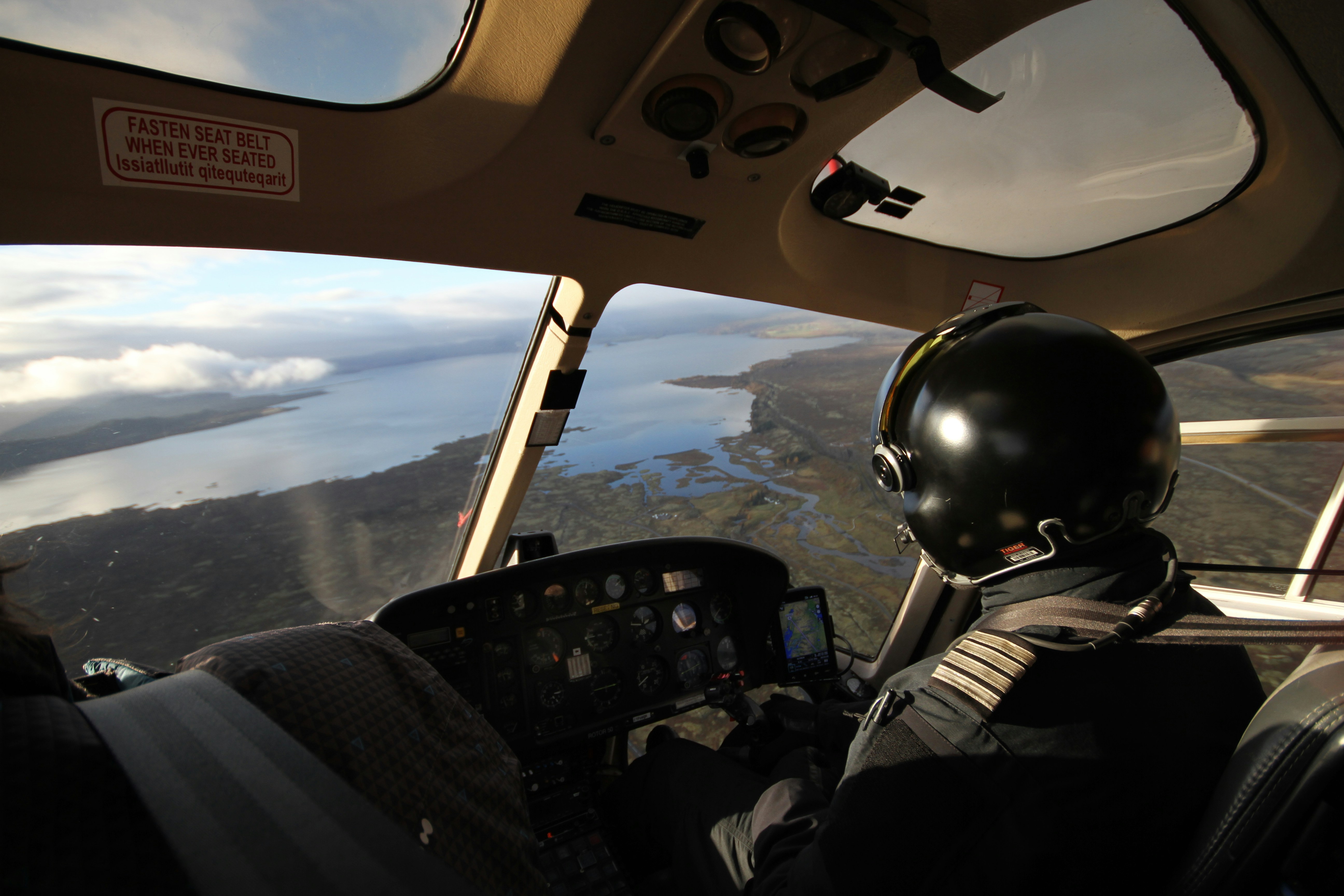 pilot near body of water during daytime, Taking a flight over Iceland with a helicopter. Just above Reykjavik.