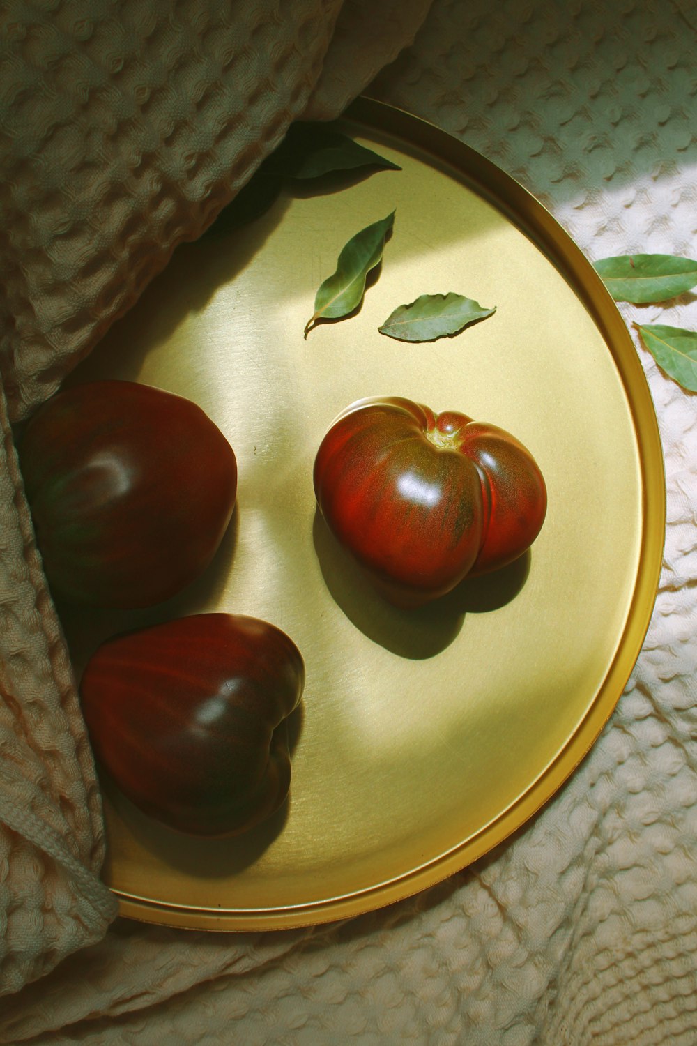 Tres tomates rojos en una bandeja dorada