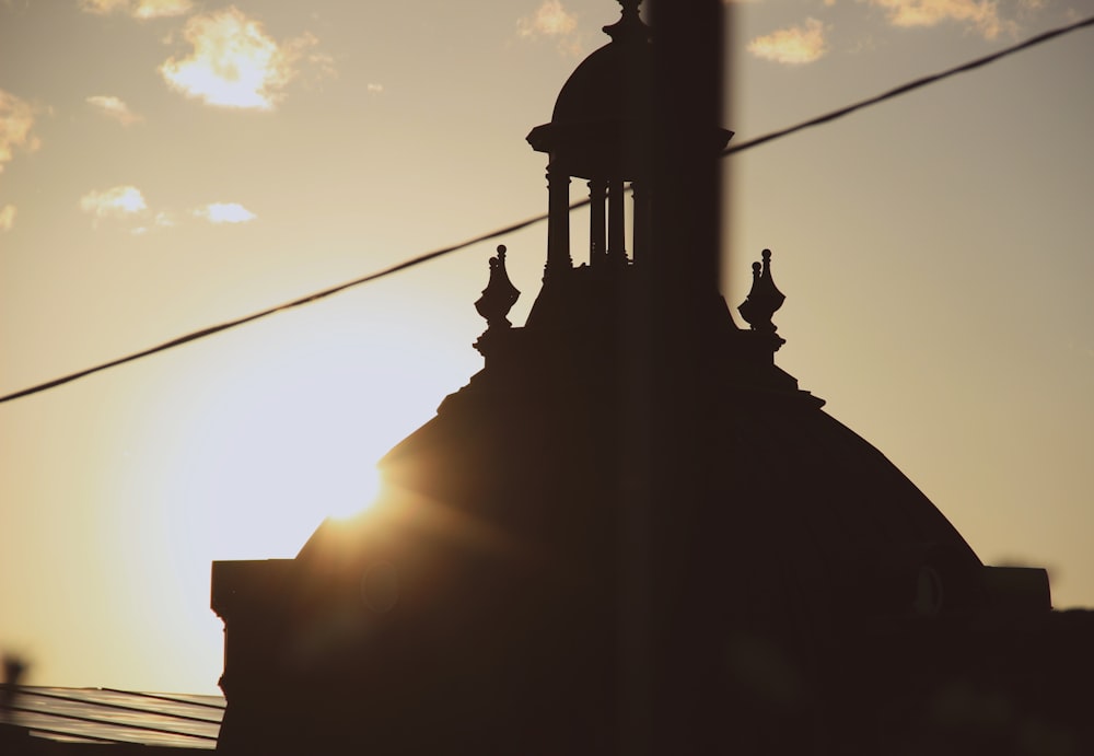 the sun is setting behind a building with a steeple