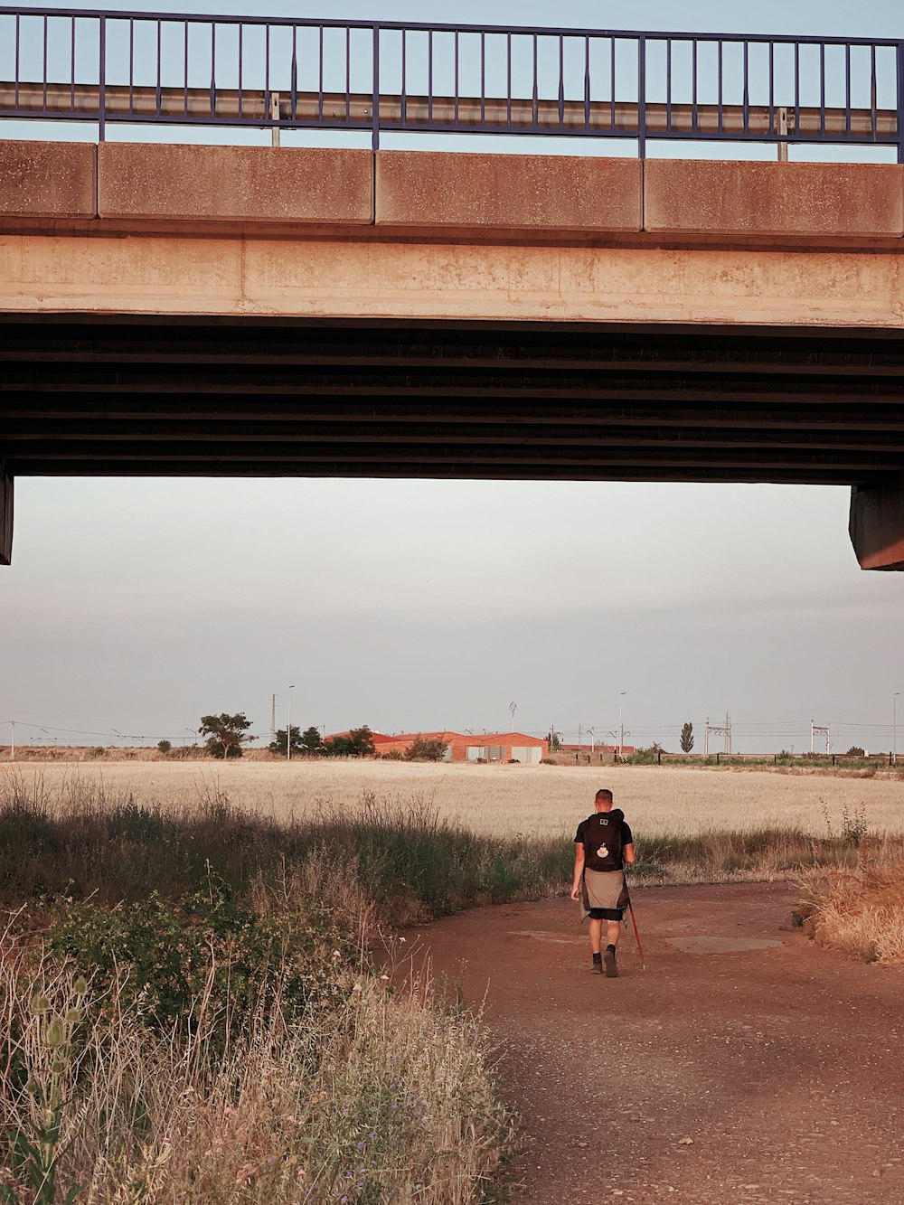 homme marchant sur la route sous le pont pendant la journée