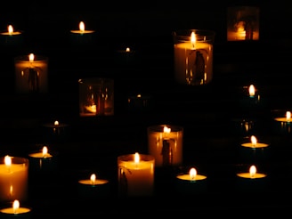 Lit yellow candles in the dark.