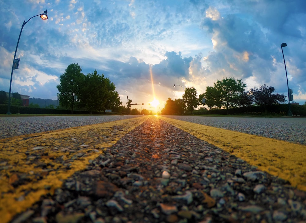 gray road under cloudy sky with sun