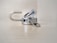 A metallic padlock is unlocked with keys inserted into it. The lock is lying on a light-colored surface with a blurred background. The keys are attached to a small metal key ring.