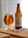 A glass of amber-colored beer is placed next to a bottle labeled 'Yorkshire Terrier' from York Brewery. Both are on a wooden surface, accompanied by a bottle opener and a bottle cap, with a softly lit background featuring horizontal blinds.