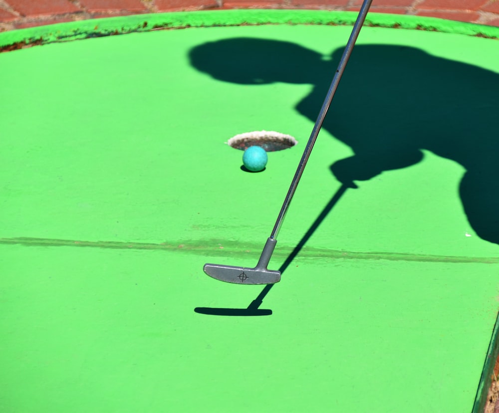 pessoa jogando golfe e bola prestes a atirar no buraco