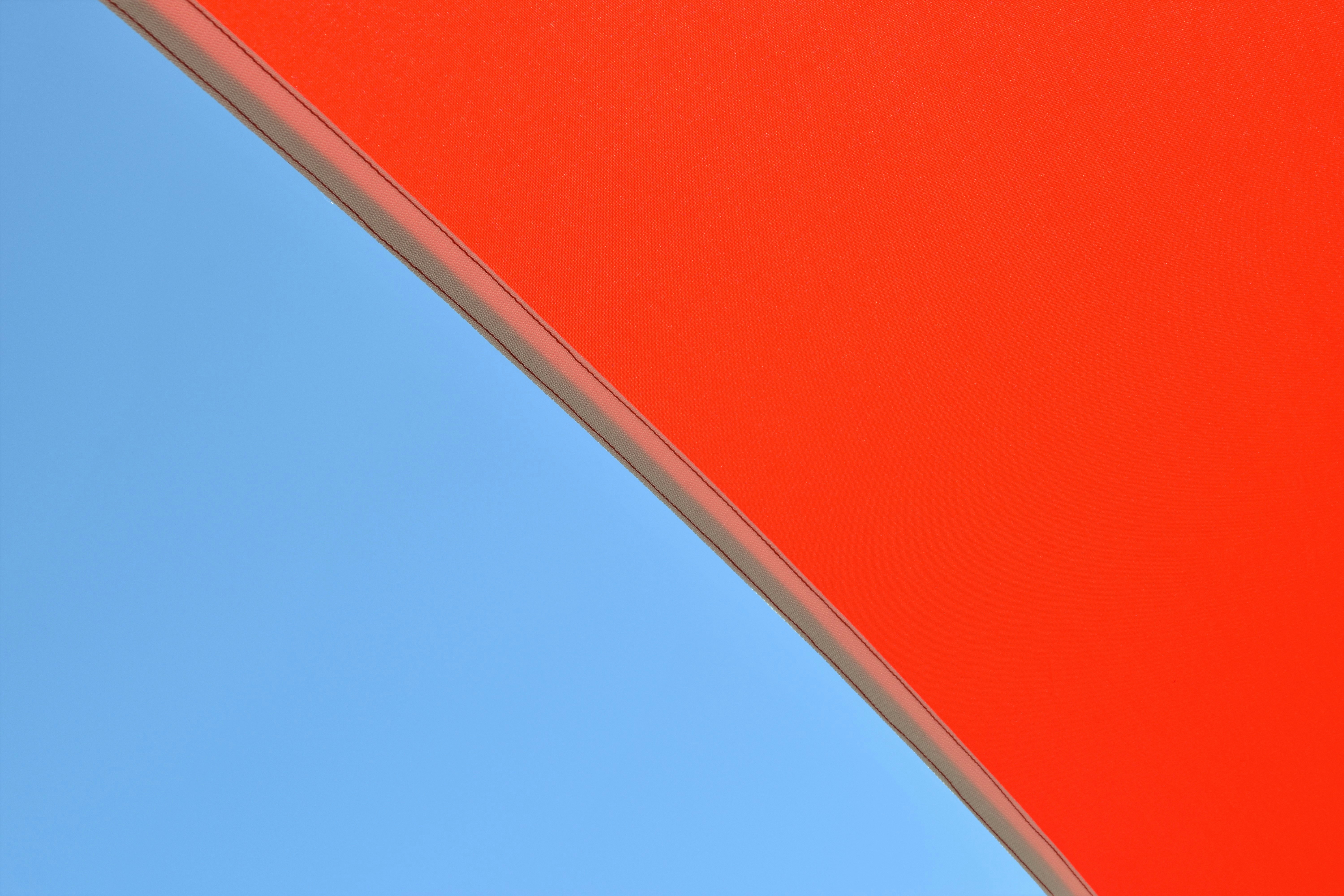 Un primer plano de un paraguas rojo con un cielo azul en el fondo
