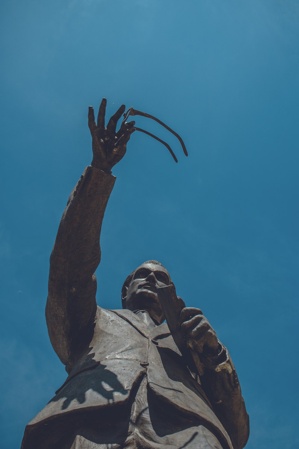 man themed statue under blue sky