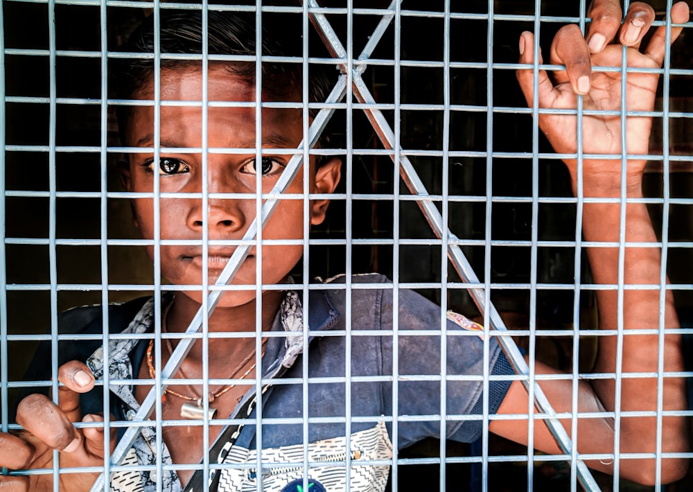 boy standing beside gray metal screen