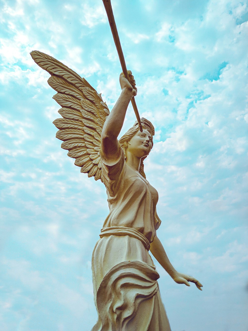angel statue under white clouds and blue sky during daytime