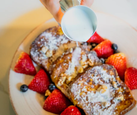 A vibrant plate featuring cinnamon swirl French toast topped with fresh strawberries and a dusting of powdered sugar.