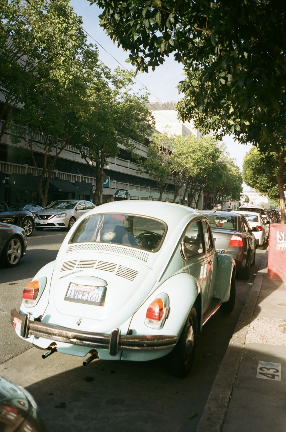 white Volkswagen Beetle parked besides gray sedan