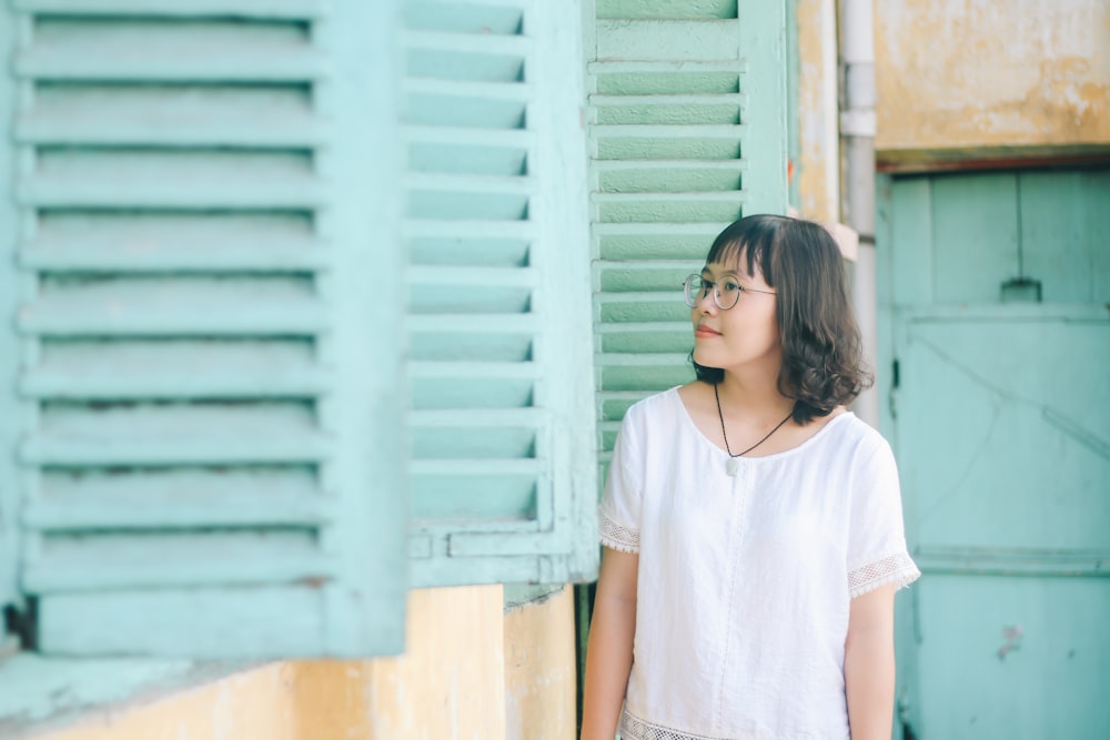 woman wearing white blouse standing beside window