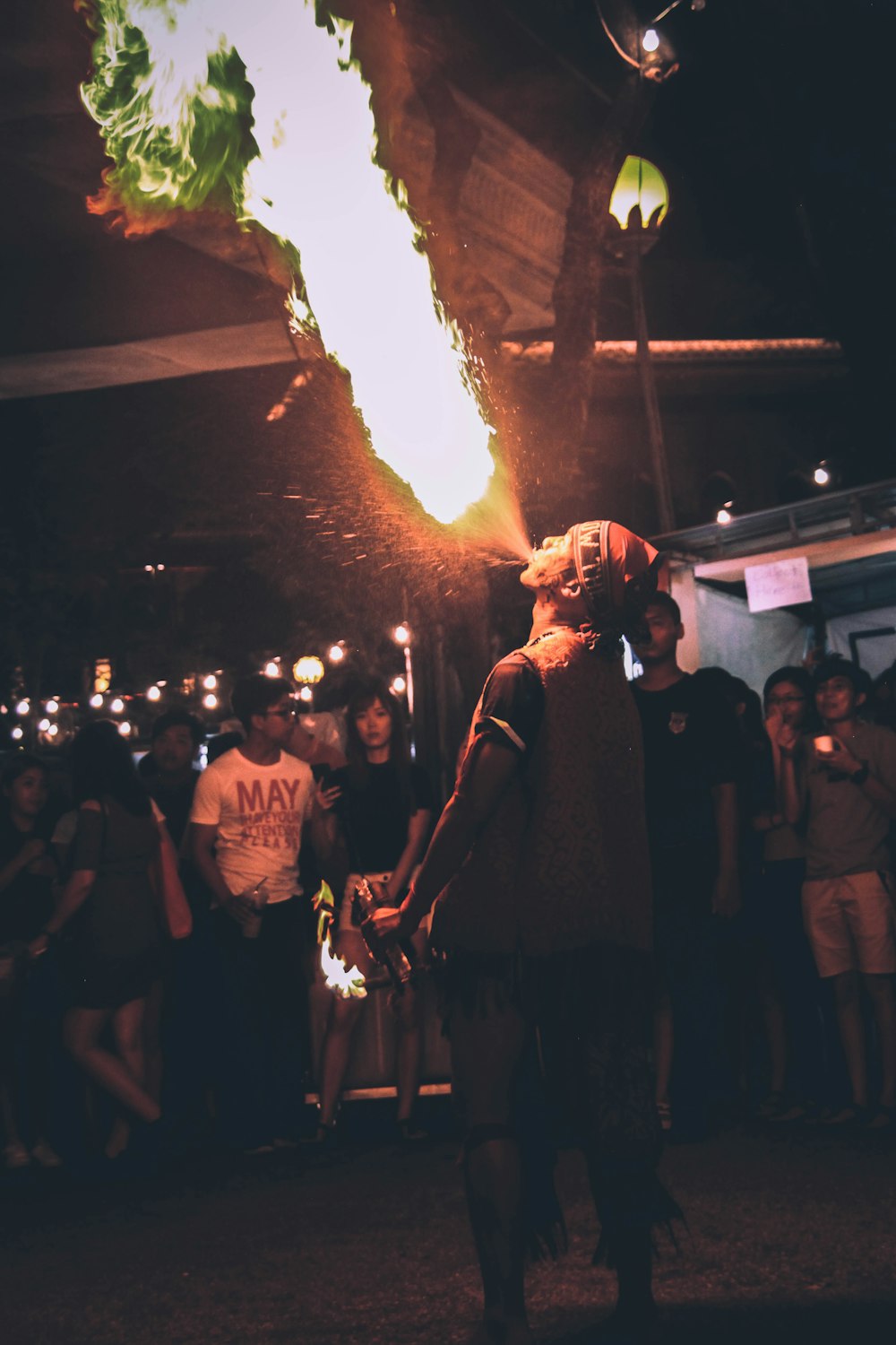 man wearing orange bandana blowing fire