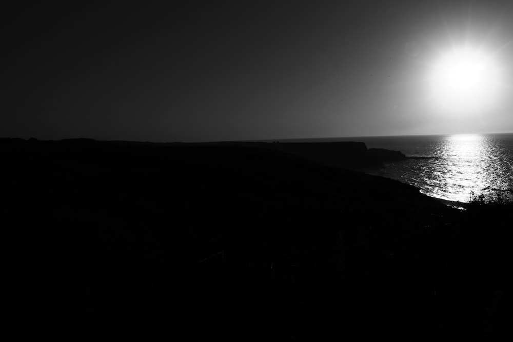 a black and white photo of the ocean at night