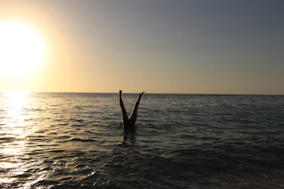 person showing legs on body of water during sunset