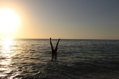 person showing legs on body of water during sunset