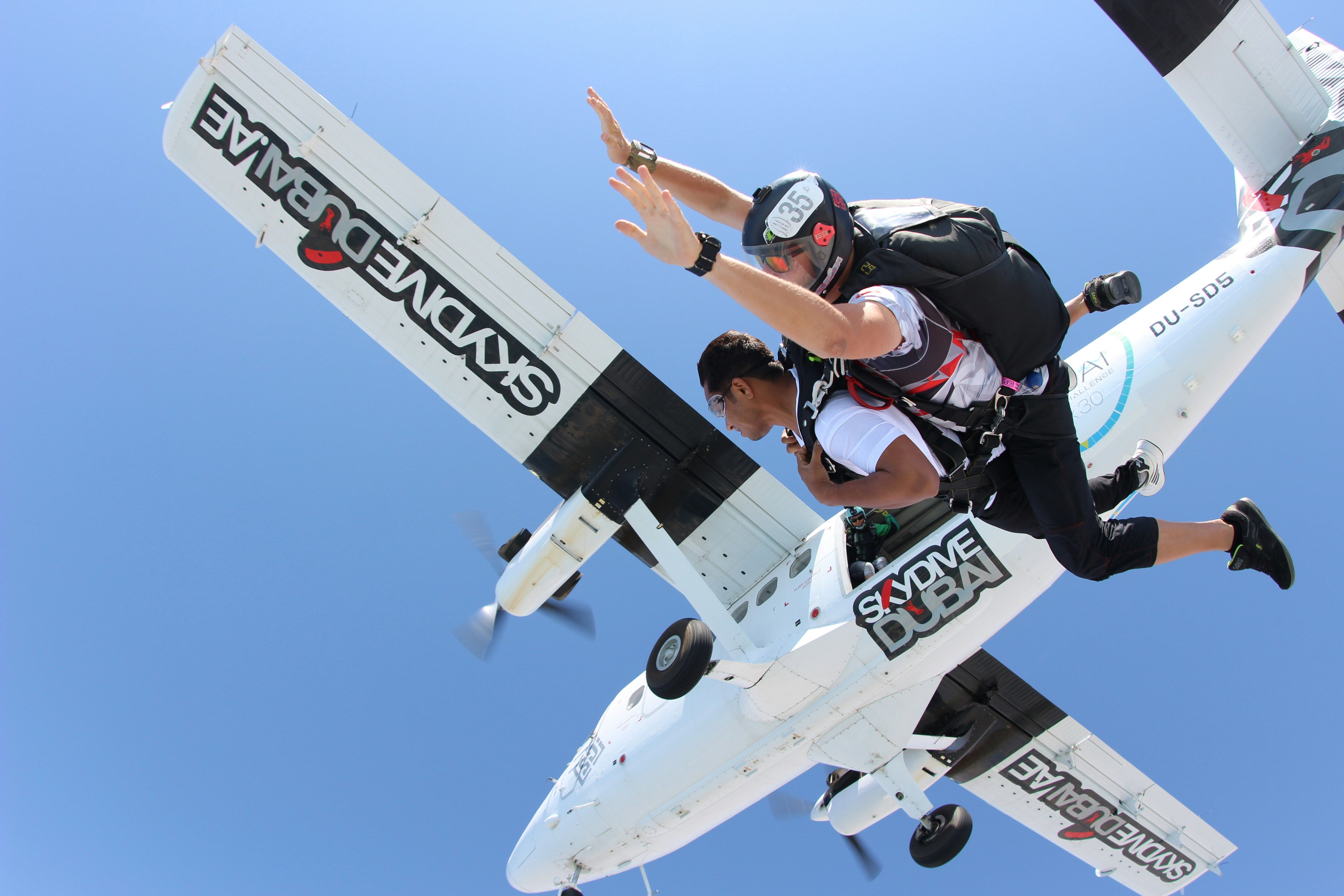 two men sky diving below airplane during day