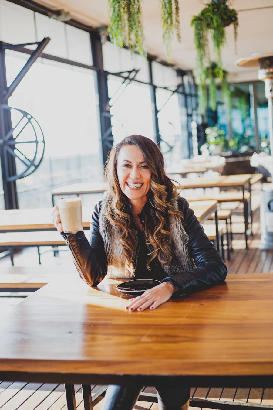 A restaurant owner smiling beside a table inside her eatery