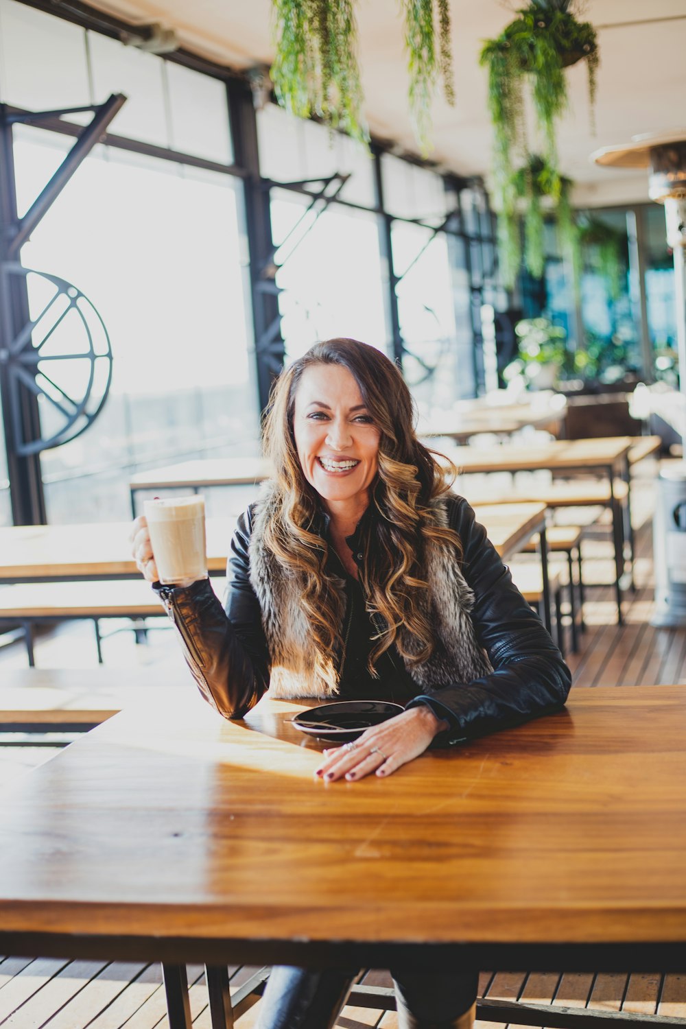 woman smiling and sitting beside table inside eatery