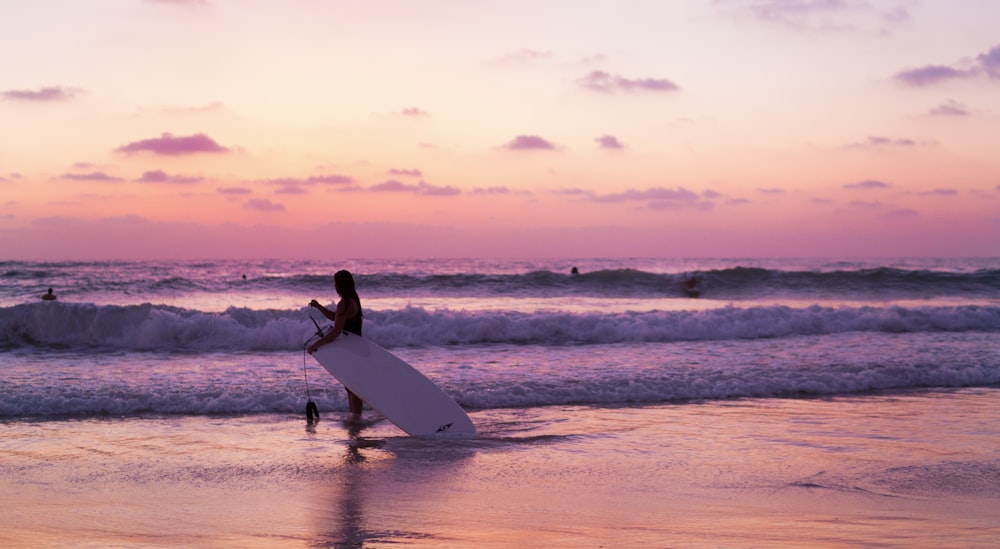 person holding surfboard on seashore