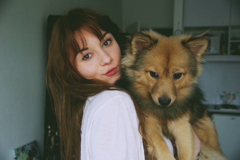 woman carrying brown puppy