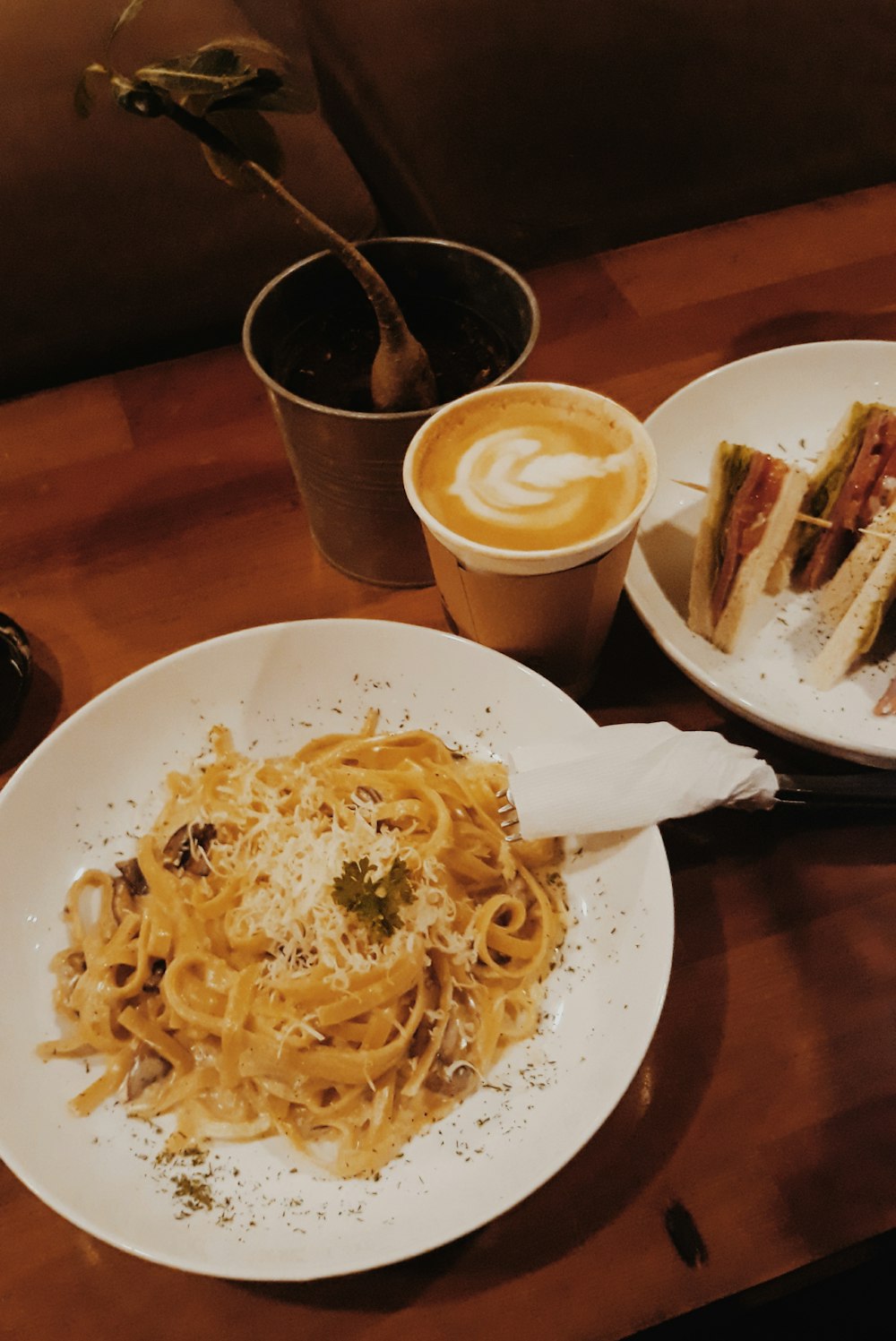 pasta on plate beside latte