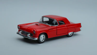 Vintage style red and black muscle car miniature on a reflective surface