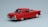 A classic red vintage car model is positioned against a plain light gray background. The car features a sleek, shiny surface with chrome accents on the bumpers and hubcaps. Its design highlights round tail lights and elegant curves typical of mid-20th-century automobiles.