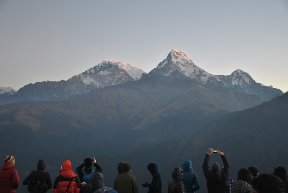 people gathering on highland across the snow-capped mountains