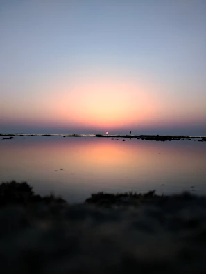 A serene outdoor scene with a person reflecting while watching a sunset.