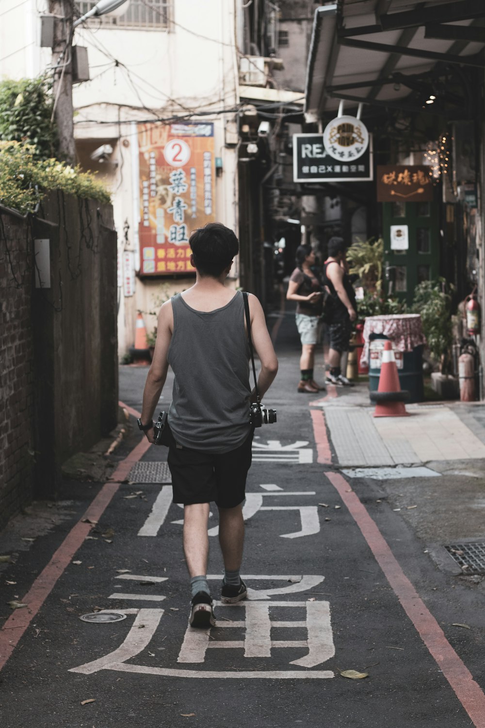 man in gray tank top walking on road