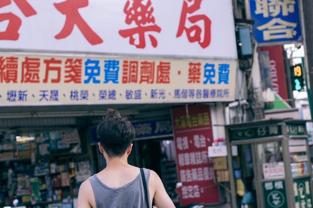 person wearing gray tank top walking on street during daytime